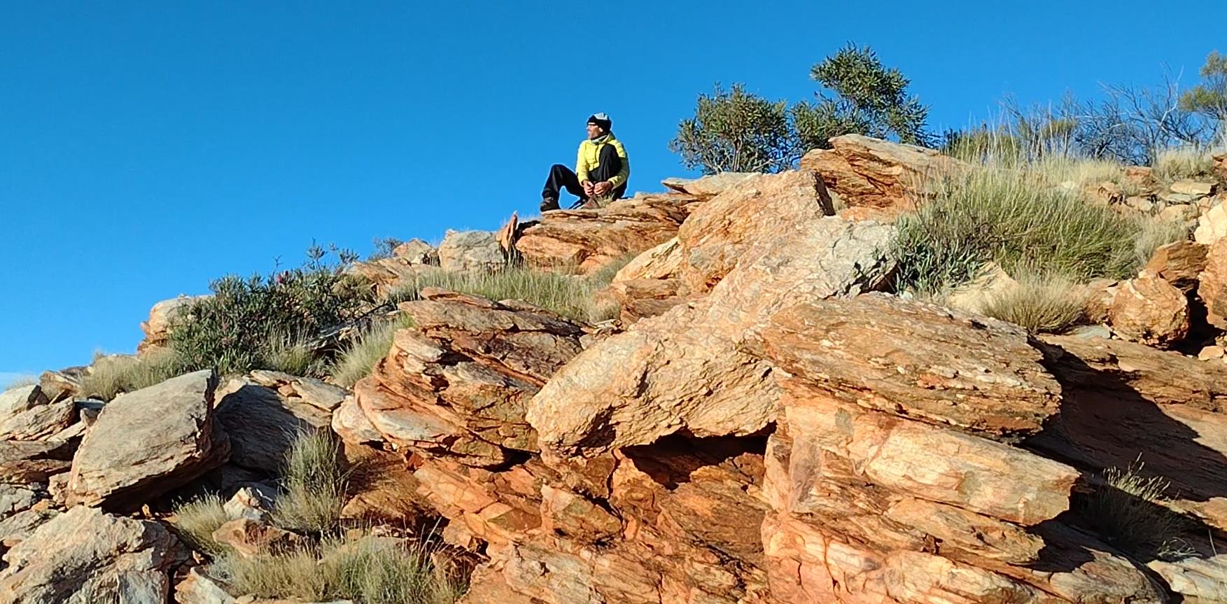 Fraser removing some gravel from a boot while he looks back towards the summit of Sonder.